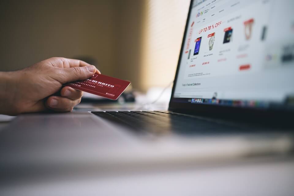 Persona adicta a las compras con su tarjeta frente al computador