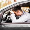 Joven decepcionado en su auto, esperando la multa por conducir sin licencia