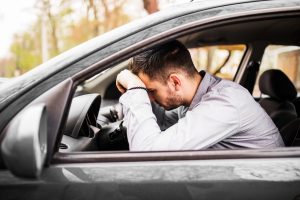 Joven decepcionado en su auto, esperando la multa por conducir sin licencia