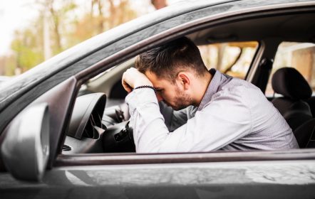 Joven decepcionado en su auto, esperando la multa por conducir sin licencia